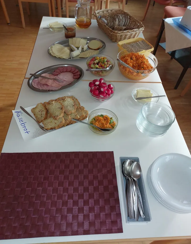 Gedeckter Abendbrottisch im Speisesaal mit Brot, Aufschnitt und Salaten