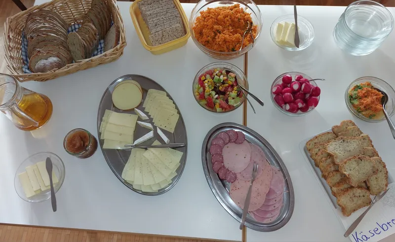 Abendbrot auf dem Tisch: Brot, Käse, Wurst, Radieschen und Salate