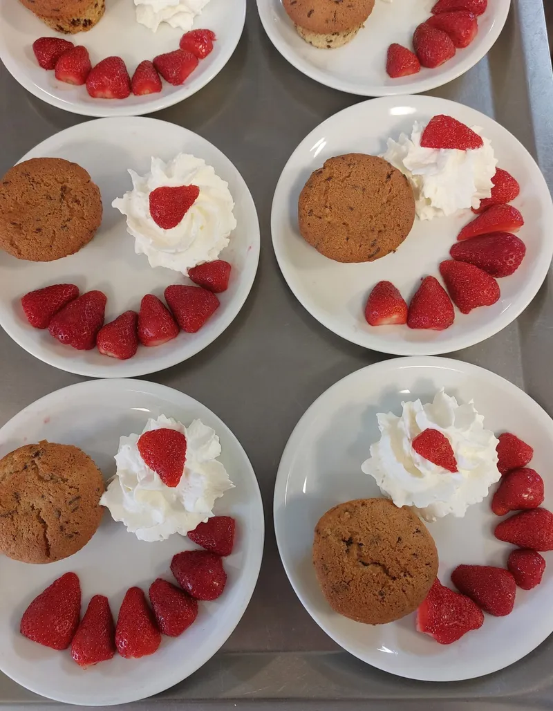 Teller mit Muffins, Sahne und Erdbeeren