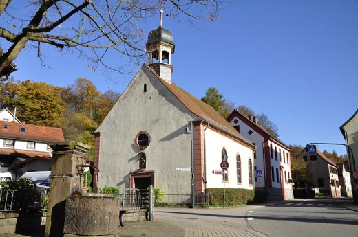 Kirchengebäude an einer Straße, davor ein Brunnen