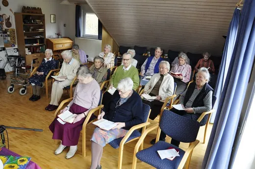 Mehrere Frauen sitzen im Halbkreis, viele mit einem Blatt in der Hand