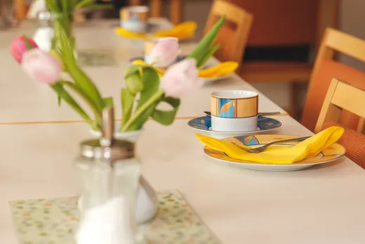 Gedeckter Tisch mit Tulpen, Tasse und gelber Serviette