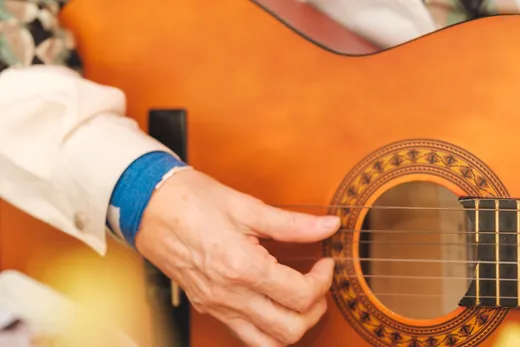 Eine Hand greift in die Saiten einer Gitarre