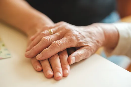 Eine Hand liegt auf der Hand einer älteren Person