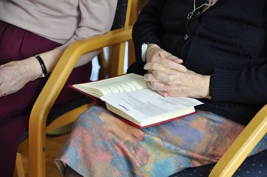 Hände halten ein aufgeschlagenes Buch auf dem Schoß