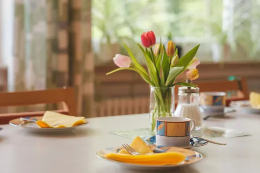 Gedeckter Tisch am Fenster mit Tulpenstrauß