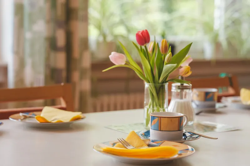 Gedeckter Tisch am Fenster mit Tulpenstrauß